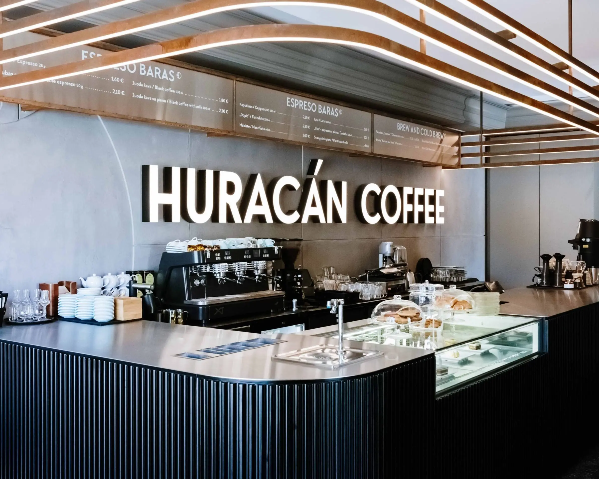 Šviečiantis Huracan Coffee logotipas virš kavos baro
