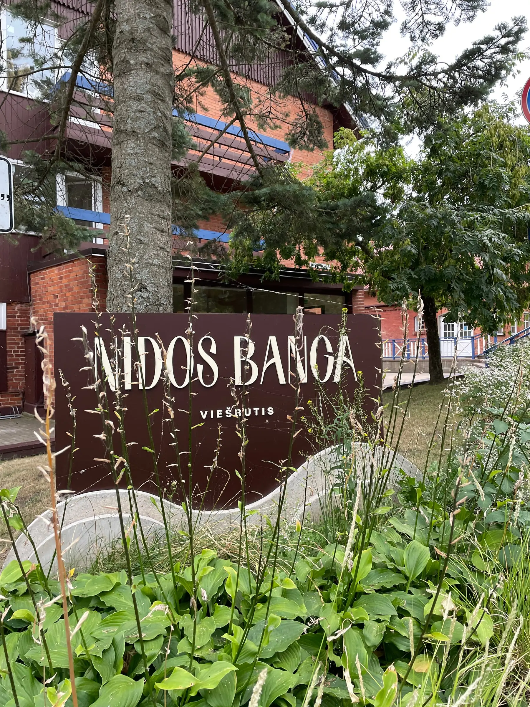 Viešbučio „Nidos banga“ iškaba su tūrinėmis raidėmis tarp želdinių